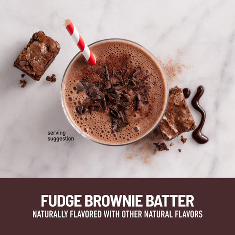 Chocolate smoothie with a red and white straw, surrounded by fudge brownie pieces on a marble surface.