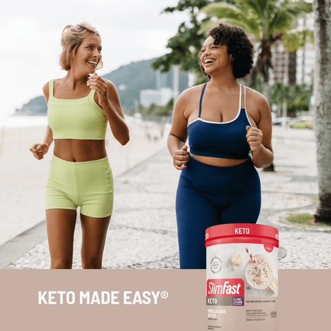 Two women in athletic wear walking outdoors with a SlimFast Keto product container.