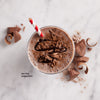 Top view of a glass on a stone countertop containing prepared SlimFast High Protein Creamy Chocolate Smoothie Mix